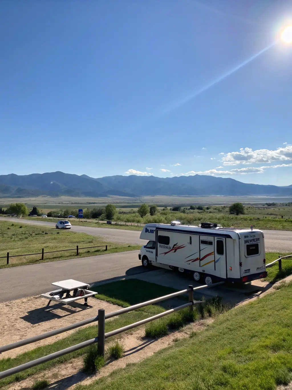 A high-quality photograph of a modern RV parked in a scenic campground with mountains in the background, showcasing the freedom and adventure associated with RV travel, for Rivera Insurance Agency's website.
